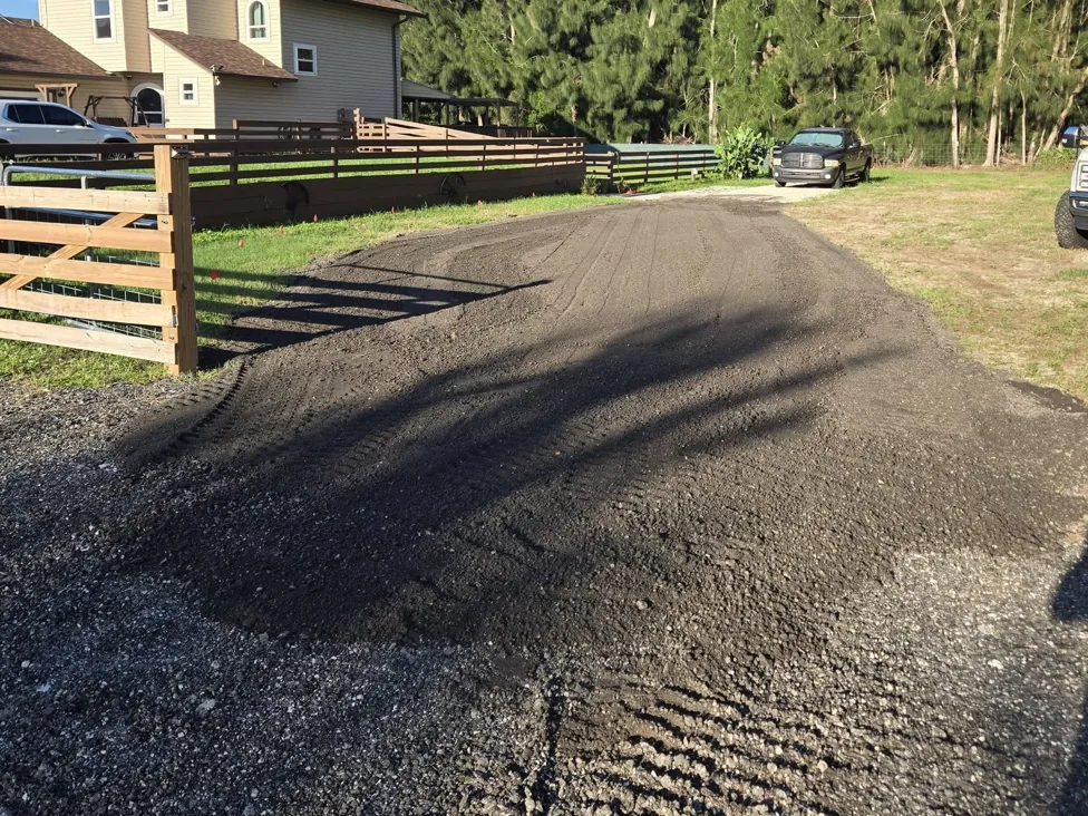 Freshly spread and track packed gravel driveway along a board fence, gravel driveways