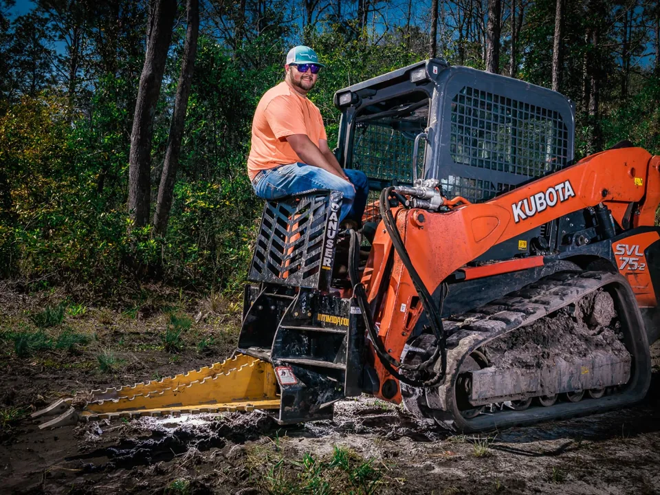 Track loader with a tree puller attachment working a wooded lot, land clearing