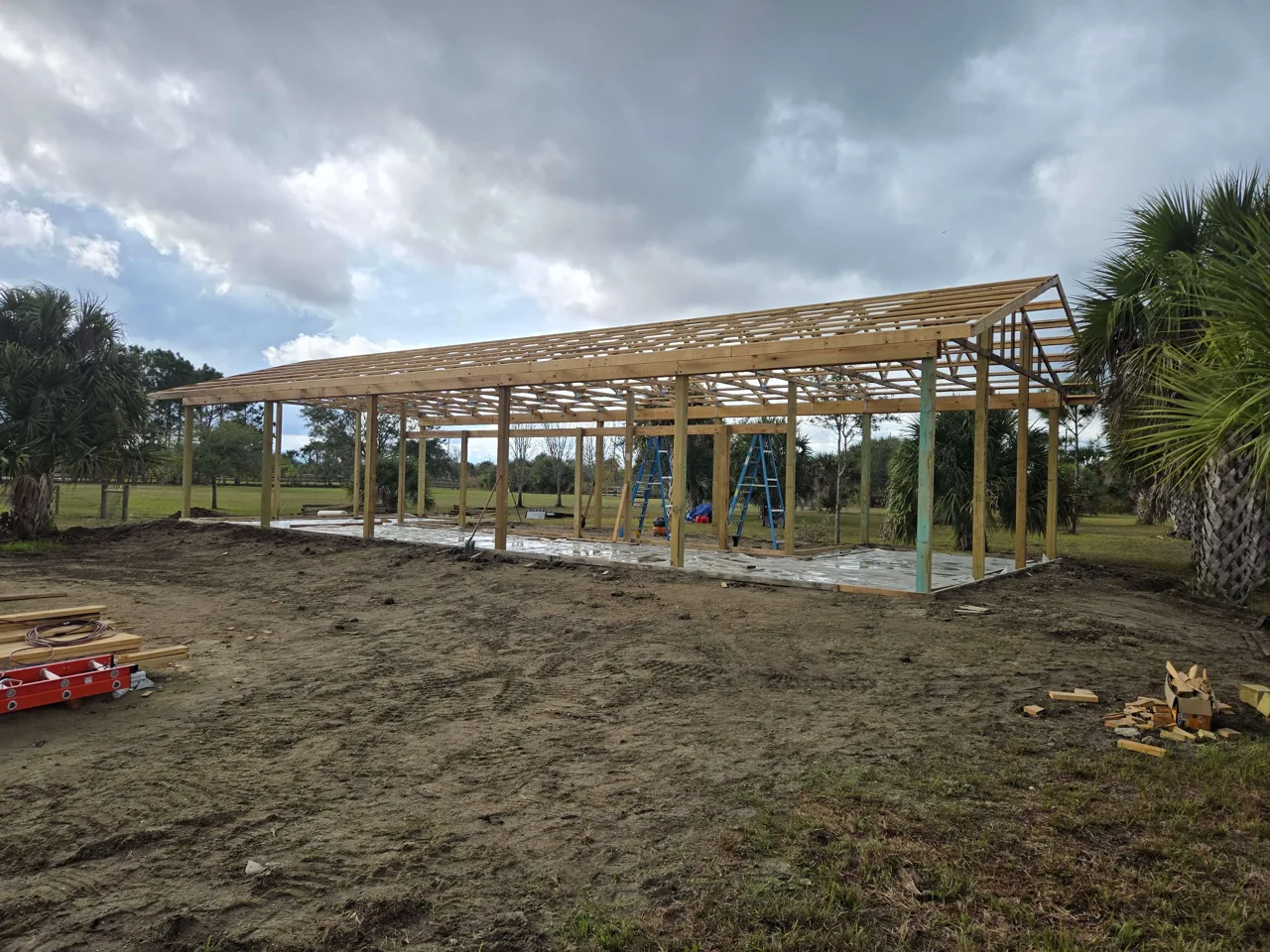 Pole barn going up with posts, trusses and purlins set on a cleared pad, pole barns